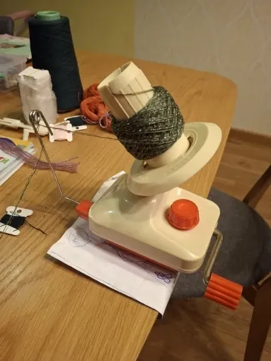 Ball winder clamped to a wooden table with a green yarn ball on the spindle, photo from a verified buyer